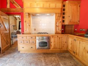 uma cozinha com armários de madeira e um forno com placa de fogão em Woodland Lodge em Alfreton
