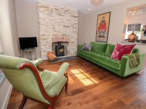 a living room with a green couch and a fireplace at 2 Court Cottages in Kingsbridge