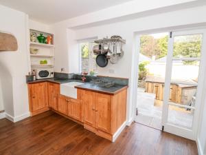 a kitchen with wooden cabinets and a large window at 2 Court Cottages in Kingsbridge