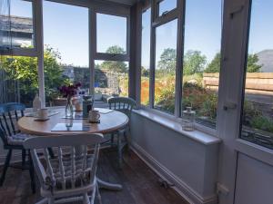 a table and chairs in a room with windows at Moelwyn View Cottage in Blaenau-Ffestiniog