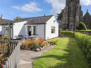 a white house with a garden and a church at Church Gate Cottage in Beaumaris