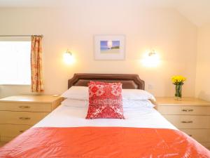 a bedroom with a bed with a red pillow on it at Cornflower Cottage in Saint Columb Major