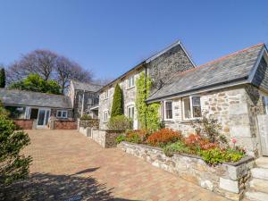 an old stone house with a brick driveway at Cornflower Cottage in Saint Columb Major