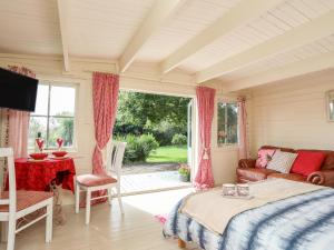 a bedroom with a bed and a couch and a window at Songbird Hideaway in Pwllheli