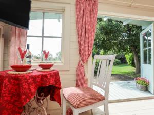 a porch with a table and chairs and a window at Songbird Hideaway in Pwllheli