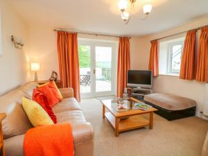 a living room with a couch and a tv at Cornflower Cottage in Saint Columb Major