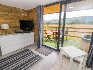 a living room with a tv and a large window at Cilan Lodge in Corwen