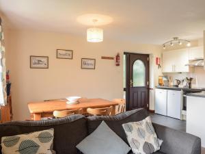 a living room with a table and a kitchen at Campion Cottage in Bude