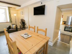 comedor con mesa y TV en la pared en Bwthyn Pennant, en Llanfihangel-y-pennant
