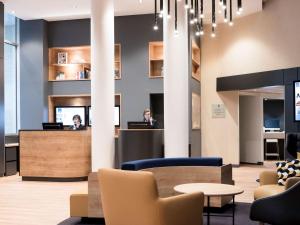 a lobby with two people sitting at a counter at Novotel Château de Versailles in Versailles
