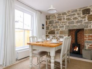 
a dining room table with a fireplace in front of it at Alice Cottage in Penzance
