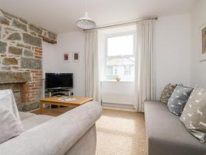 
a living room filled with furniture and a tv at Alice Cottage in Penzance
