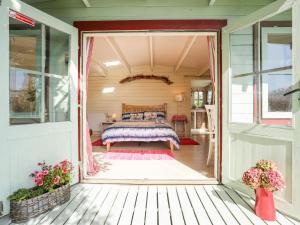 een slaapkamer in een tiny house met een bed op een veranda bij Songbird Hideaway in Pwllheli