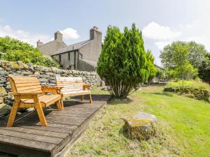 two wooden benches sitting on a wooden deck in a yard at Bwthyn Pennant in Llanfihangel-y-pennant