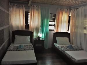 2 letti posti in una stanza con tende di Oasis Balili Heritage Lodge a Città di Tagbilaran