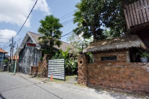 a house with a brick wall next to a street at Vande Guest House in Canggu