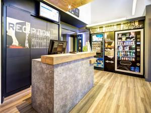 a red elephant store with a counter and a refrigerator at ibis Budget Caen Memorial in Caen