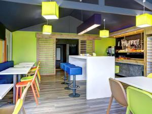 un restaurante con mesas y sillas coloridas y un bar en ibis budget Caen Hérouville, en Hérouville-Saint-Clair