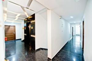a hallway in a building with white walls and black tile floors at X by Bloom l Manyata in Bangalore