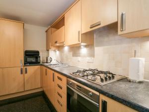 uma cozinha com armários de madeira e um forno com placa de fogão em 7 Riverside Gardens em Inverness