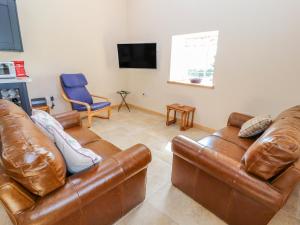 een woonkamer met 2 leren banken en een tv bij The Loft in Mold