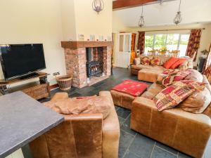 a living room with couches and a flat screen tv at 1 Homecroft Bungalows in Saundersfoot