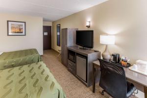 a hotel room with a bed and a desk with a television at Quality Inn & Suites Plattsburgh in Plattsburgh
