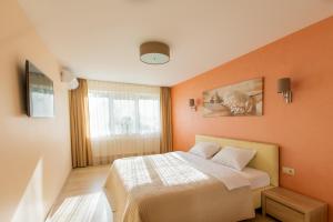 1 dormitorio con paredes de color naranja, 1 cama y ventana en Audros Apartamentai, en Kaunas