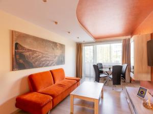 a living room with an orange couch and a table at Audros Apartamentai in Kaunas