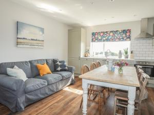 una sala de estar con un sofá y una mesa en Southcott Apartment, en Trearddur