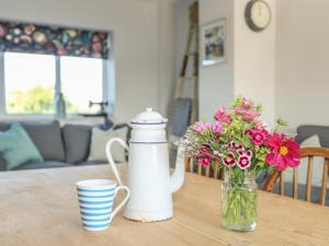 Un jarrón de flores y una taza sobre una mesa. en Southcott Apartment, en Trearddur