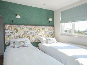 2 camas en una habitación con una pared verde en Southcott Apartment, en Trearddur