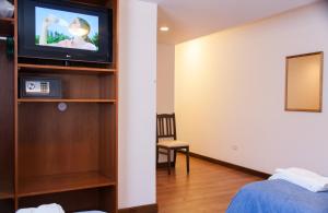 a room with a bed and a tv on a wall at Hotel Premier Bariloche in San Carlos de Bariloche