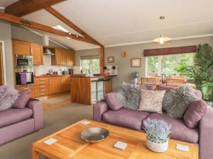 a living room with two purple couches and a kitchen at Bulmer Farm Lodge in Malton
