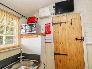 a kitchen with a sink and a door with a microwave at Shepherds Hut - The Hurdle in Milford Haven