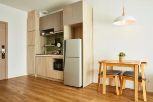 a kitchen with a white refrigerator and a table at Serenity Hotel and Spa Kabinburi in Kabin Buri