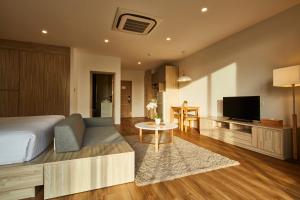 a bedroom with a bed and a living room with a tv at Serenity Hotel and Spa Kabinburi in Kabin Buri