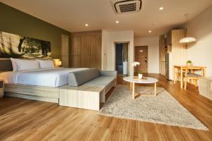 um quarto com uma cama, um sofá e uma mesa em Serenity Hotel and Spa Kabinburi em Kabin Buri