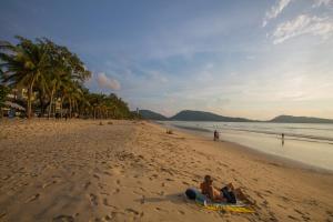 two people sitting on a towel on the beach at Royal Beach Residence in Patong Beach