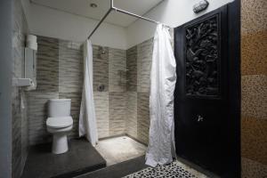 a bathroom with a toilet and a black door at Vande Guest House in Canggu