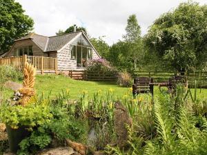 a yard with a house and a garden with flowers at Kidcleugh Hide in Duns