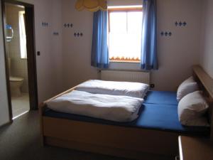 a bedroom with a bed with a window and blue curtains at Ferienwohnungen Haberberger in Pottenstein