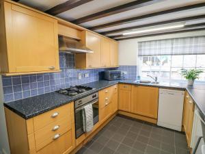 une cuisine avec des armoires en bois et un four à plaques de cuisson dans l'établissement End cottage, à Ashbourne