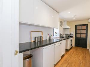 a kitchen with white cabinets and a black counter top at Puddleducks in Sherborne