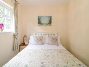 a bedroom with a white bed with pink pillows at The Roost in Camborne