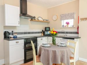 una cocina con una mesa con un jarrón de flores. en The Roost en Camborne