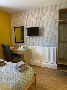 um quarto com uma cama, uma secretária e uma televisão em Central Hotel em Sutton in Ashfield