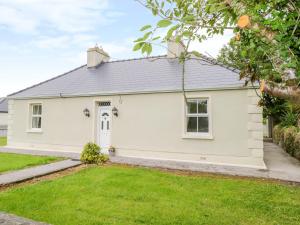 a white house with a lawn in front of it at Cherry Tree Cottage in Ballintober