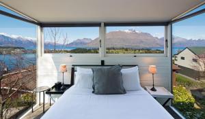 a bedroom with a bed and a large window at Panoramic: farmhouse theme with shared spa pool in Queenstown +4 photos