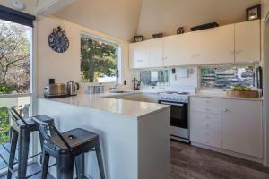 a kitchen with white cabinets and a counter with stools at Panoramic: farmhouse theme with shared spa pool in Queenstown